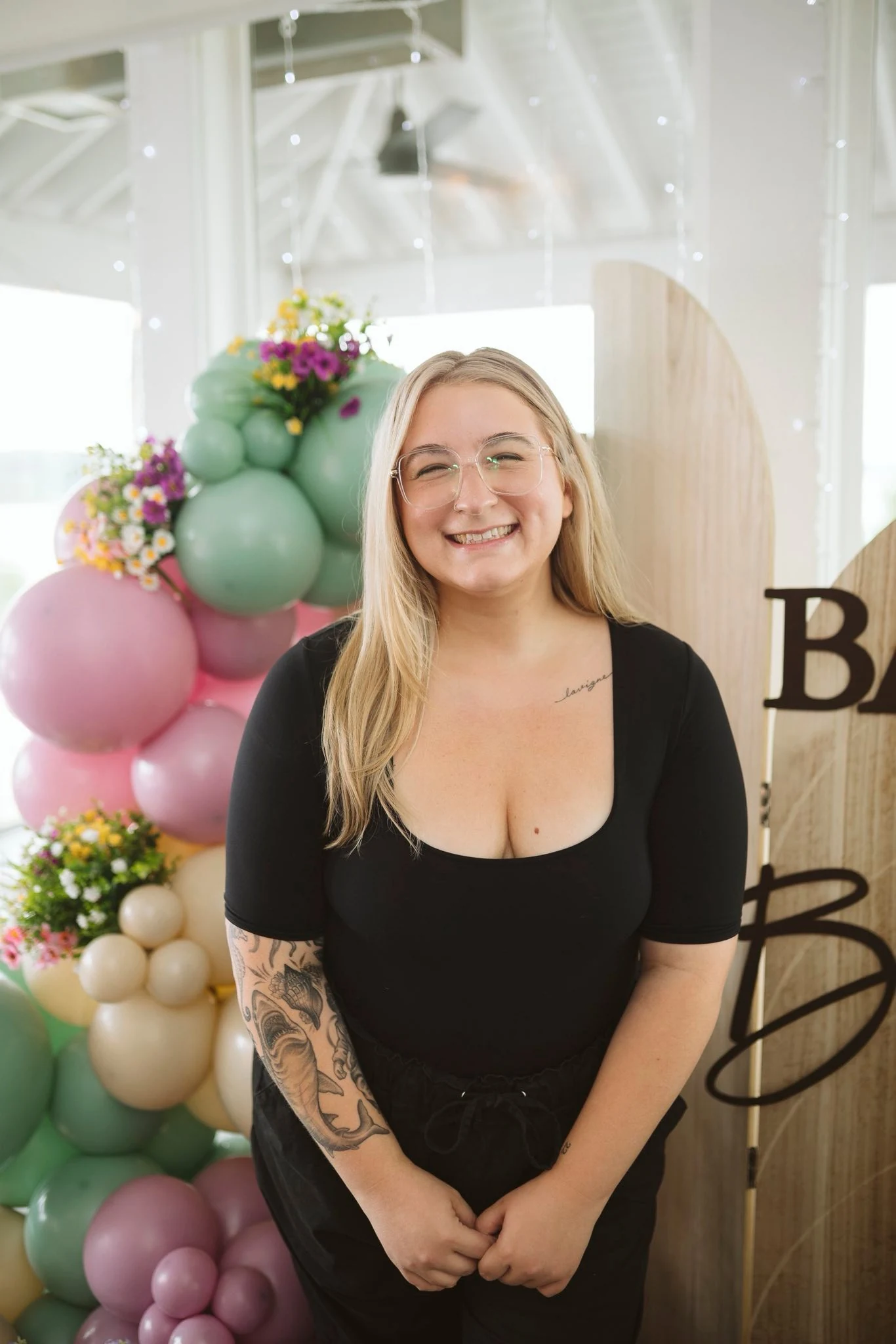 Kelsie, owner of Parties by Kels, smiling in front of her balloon installation